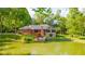 A lush landscaped backyard features a pond and beautiful home with solar panels on a sunny day at 1633 W 200 North, Greenfield, IN 46140