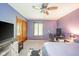 Carpeted bedroom with purple walls, wood closet doors, ceiling fan and TV on storage cabinet at 1633 W 200 North, Greenfield, IN 46140