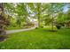 A charming brick home is seen behind a lush green lawn and driveway, and is surrounded by mature trees at 1633 W 200 North, Greenfield, IN 46140