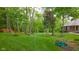 A verdant green lawn is surrounded by trees and landscaping and is partially seen from behind a house at 1633 W 200 North, Greenfield, IN 46140