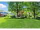 Spacious backyard with lush lawn, mature trees, and charming home exterior, fenced in for privacy at 1748 Sweet Gum Dr, Indianapolis, IN 46260