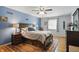 Comfortable bedroom with hardwood floors, a ceiling fan, and a serene blue accent wall at 1748 Sweet Gum Dr, Indianapolis, IN 46260