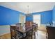Bright dining room boasts blue walls, chair rail, hardwood floors, and a modern chandelier at 1748 Sweet Gum Dr, Indianapolis, IN 46260