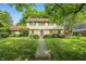 Inviting two-story home with stone accents, green lawn, mature trees, and walkway to front door at 1748 Sweet Gum Dr, Indianapolis, IN 46260