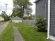 A charming backyard featuring a detached garage, grassy lawn, stone pathway, and partial view of the house at 203 W 3Rd St, Sheridan, IN 46069
