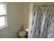 Bathroom featuring a white toilet, window and a shower with a blue patterned shower curtain at 203 W 3Rd St, Sheridan, IN 46069