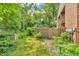 Exterior view of fenced backyard with mature landscaping, gate, and brick home at 2267 Rome Dr # A, Indianapolis, IN 46228