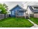 Quaint blue home with a backyard, featuring a small wooden deck and staircase at 3764 Ruckle St, Indianapolis, IN 46205