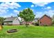 Large backyard featuring a fire pit, lush greenery, and blue sky at 4123 S Village Row, New Palestine, IN 46163