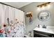 Charming bathroom featuring a floral shower curtain, stylish vanity, and a rustic wooden accent shelf at 4123 S Village Row, New Palestine, IN 46163