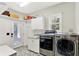 Well-lit laundry room with stainless steel washer and dryer, storage cabinets, utility sink, and backyard access at 4123 S Village Row, New Palestine, IN 46163