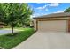 The garage of a well-manicured home, with grass, and a tree, under a partly cloudy sky at 423 Bent Tree Ln, Indianapolis, IN 46260
