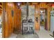 Rustic living room with wood-paneled walls and a charming wood-burning stove with stone backsplash at 429 E Hoover Dr, Nineveh, IN 46164