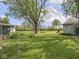 A spacious backyard with a shed, garage and a screened in porch on the house, all surrounded by lush greenery at 4305 Clinton St, Lawrence, IN 46226