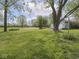 Expansive backyard featuring mature trees, a storage shed, and open green space at 4305 Clinton St, Lawrence, IN 46226