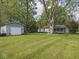 A well-manicured lawn featuring a shed, garage and a house with screened in porch and lush greenery all around at 4305 Clinton St, Lawrence, IN 46226