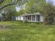 View of the charming white house with a screened in porch and large, well-maintained backyard and lush greenery at 4305 Clinton St, Lawrence, IN 46226