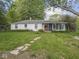Charming home with a screened in porch surrounded by lush greenery and a stone pathway, all situated in a spacious yard at 4305 Clinton St, Lawrence, IN 46226