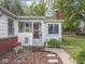 Close up of charming enclosed front porch with colorful welcome decorations and brick foundation accents at 4305 Clinton St, Lawrence, IN 46226