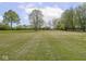 Picturesque view of a sprawling green field, dotted with mature trees under a bright sky with fluffy white clouds at 4305 Clinton St, Lawrence, IN 46226
