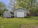 A well-maintained backyard featuring both a shed and a garage with a white door, with luscious green grass at 4305 Clinton St, Lawrence, IN 46226
