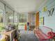 Enclosed sunroom has multiple windows, decorated with plants, seating, and garden ornaments at 4305 Clinton St, Lawrence, IN 46226
