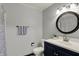 Bathroom features a round mirror over a navy vanity with a white countertop and a shower with a patterned curtain at 4623 E Windsor Ln, Columbus, IN 47201