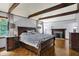 Bedroom with exposed beams, a decorative fireplace, wood floors, a large bed and matching dresser at 4623 E Windsor Ln, Columbus, IN 47201