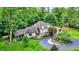 Charming home featuring lush landscaping, a circular driveway, and a serene wooded backdrop at 4623 E Windsor Ln, Columbus, IN 47201