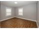 A clean, empty bedroom features wood-look floors, two windows, neutral walls, and white trim at 4933 W 13Th W St, Speedway, IN 46224