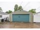 View of the detached garage with a teal door and siding matching the house, enhancing curb appeal at 4933 W 13Th W St, Speedway, IN 46224
