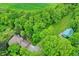 Aerial view showcases lush foliage surrounding a home with charming outbuildings and a gravel driveway at 4990 E County Road 750 S, Brownsburg, IN 46112