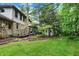 Back exterior featuring a stone facade, deck, grill, and mature trees, creating a private oasis at 4990 E County Road 750 S, Brownsburg, IN 46112