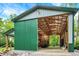 A green barn reveals a spacious interior with a partially open door, concrete flooring, and exposed wooden beams at 4990 E County Road 750 S, Brownsburg, IN 46112