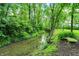 A slow moving creek is surrounded by large trees and green grass with a concrete bench on the right at 4990 E County Road 750 S, Brownsburg, IN 46112