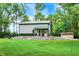 A metal pole barn features a covered porch with rocking chairs, set amidst lush greenery and a rock foundation at 4990 E County Road 750 S, Brownsburg, IN 46112