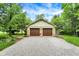 Two-car garage with stone accents and a wide gravel driveway, surrounded by mature trees at 4990 E County Road 750 S, Brownsburg, IN 46112
