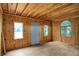 An empty room with hardwood floors and wood paneled walls, bathed in natural light from multiple windows at 4990 E County Road 750 S, Brownsburg, IN 46112