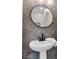 Modern powder room featuring stylish gray tile, a round mirror, and a sleek pedestal sink at 515 Lynton Way, Westfield, IN 46074