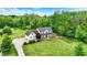 An aerial shot reveals a home with a large manicured lawn, bordered by lush trees and a charming garden area at 7380 N 225 W, Lebanon, IN 46052