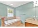 Bathroom featuring a tiled-surround bathtub with a window view and a vanity with cabinets at 7380 N 225 W, Lebanon, IN 46052