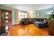 Cozy living room featuring hardwood floors, a large sectional couch, and natural light from the front windows at 8027 S 250 E, Markleville, IN 46056