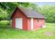 Charming outbuilding with red wood paneling, a garage door and regular door sits amid a lush green lawn and trees at 8027 S 250 E, Markleville, IN 46056