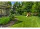 Backyard featuring a lush lawn, flower bed, mature trees, and a swing set at 9804 Wentworth Ct, Carmel, IN 46032