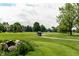 Scenic golf course view with manicured greens, mature trees, and golf cart on the path at 9804 Wentworth Ct, Carmel, IN 46032