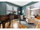 Cozy sitting area with hardwood floors, a large window, two armchairs, and a dark-stained baby grand piano at 9804 Wentworth Ct, Carmel, IN 46032