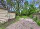 View of a backyard with gravel, overgrown grass, and access to a detached garage at 1140 Mcdougal St, Indianapolis, IN 46203