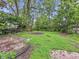 Backyard with overgrown grass and a small charred area, surrounded by trees and foliage at 1140 Mcdougal St, Indianapolis, IN 46203