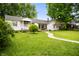 Quaint home featuring a large lawn, mature trees, and a concrete walkway at 1212 Woodlawn Ave, Indianapolis, IN 46203