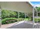 Wide shot of the covered backyard deck with built-in benches and lush greenery at 1410 Shadow Ct, Zionsville, IN 46077